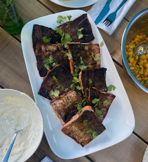 A platter of blackened salmon fillets topped with fresh cilantro