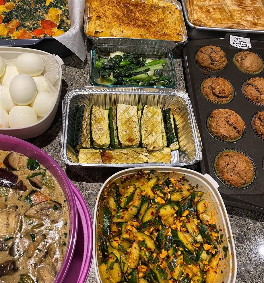 A counter of prepared dishes: spicy cucumber salad, roasted zucchini, banana chocolate muffins, boiled eggs and a mushroom soup