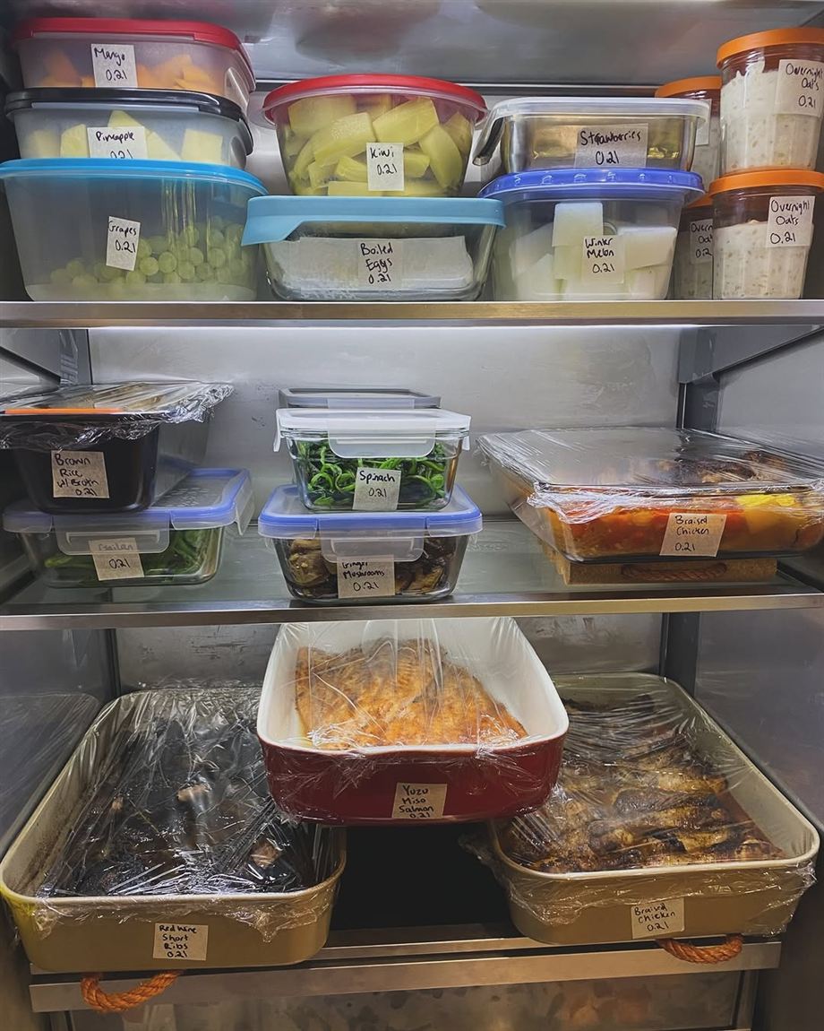 A client's fridge stocked with labelled containers: braised chicken, yuzu miso salmon, red wine short ribs, cut fruit and overnight oats