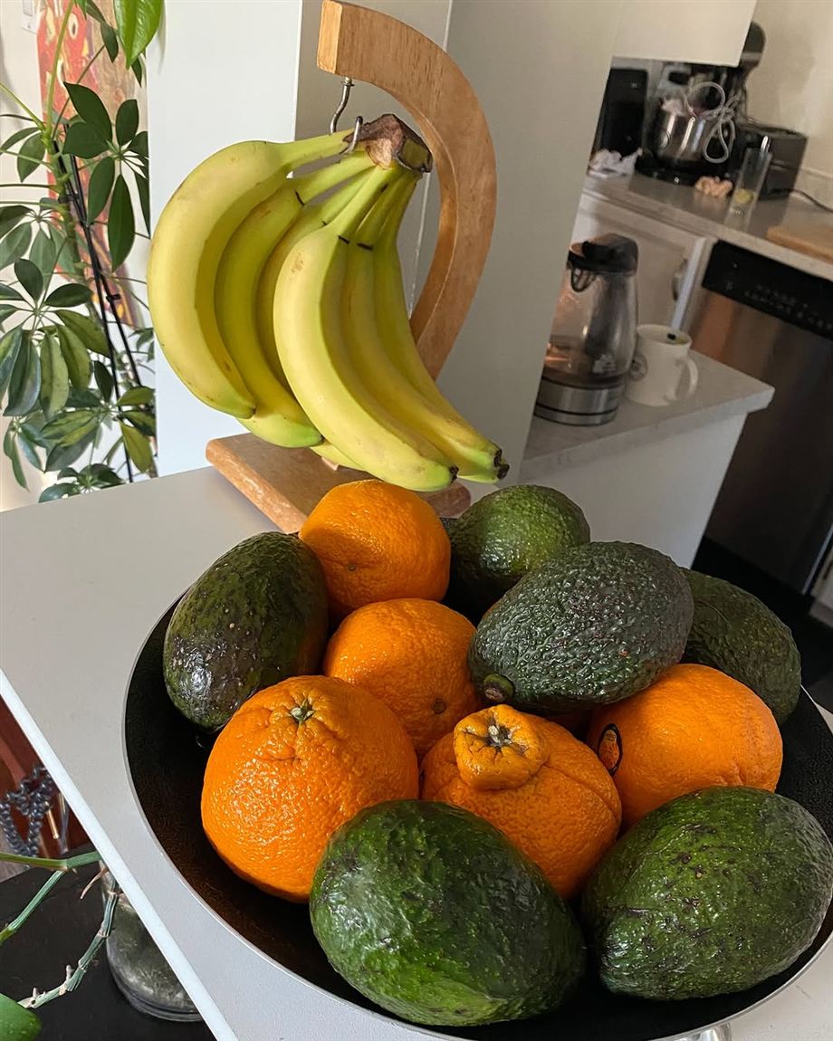 A fresh restock in a client's kitchen: a bowl of avocados and oranges beneath a bunch of bananas